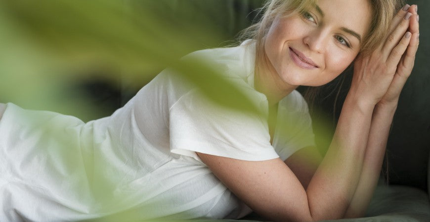 Mujer sonriente tumbada de lado, apoyando la cabeza sobre las manos
