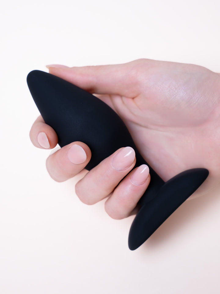 Plug anal negro sostenido en la mano