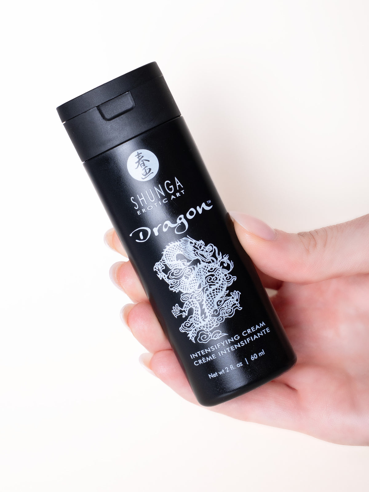 Envase de crema Dragon sostenido en la mano